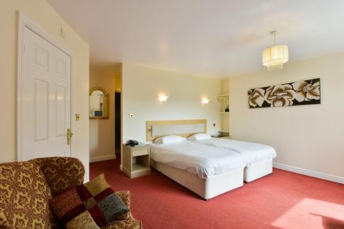 a bedroom with a white bed and a couch at Edenhall Country Hotel in Penrith
