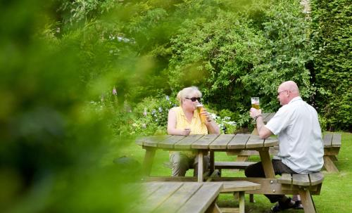 two people sitting at a picnic table in a wooded area at Edenhall Country Hotel in Penrith