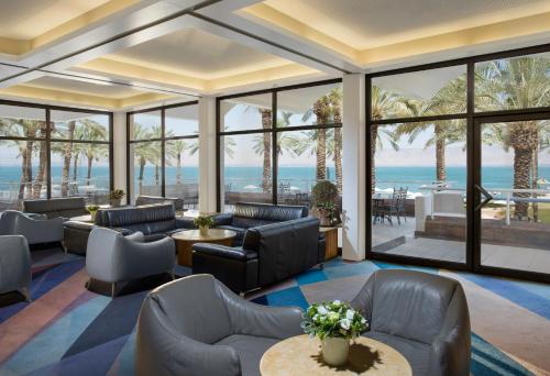 a living room with chairs and tables and windows at Gai Beach Hotel in Tiberias