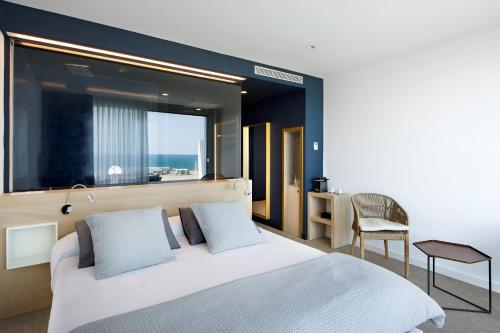 a bedroom with a bed and a window and a chair at Hotel Boutique dONNA 4* Superior in Castelldefels
