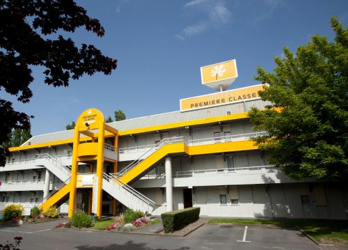 a hotel with a yellow building with a sign on it at Premiere Classe Auxerre in Monéteau