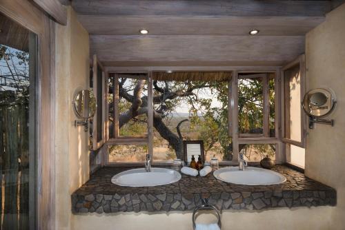two sinks in a bathroom with a window at Ongava Lodge in Okaukuejo