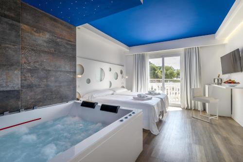 ein Bad mit einer Badewanne und einem Bett in der Unterkunft Hotel Triton Beach in Cala Ratjada