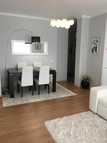 a dining room with a black table and white chairs at Apartamento Praia Da Gaivota in Quarteira