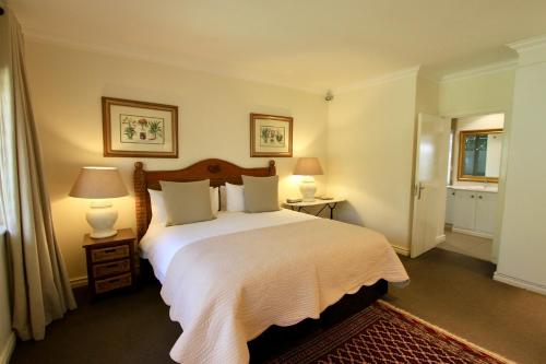 a bedroom with a large white bed with two lamps at Melrose Place Guest Lodge in Johannesburg