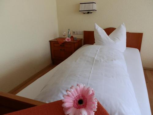 a bedroom with a white bed with a pink flower on it at Landhotel Löwen in Blumberg