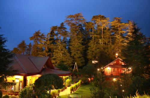 a house with a garden in front of a forest at The Chalets Naldehra in Shimla