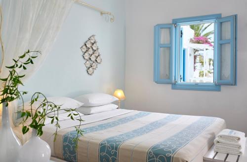 a bedroom with a bed with a blue window at Folegandros Apartments in Chora Folegandros