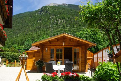 a cabin with a table and chairs in front of a mountain at Haus Kohlberghof in Bichlbach