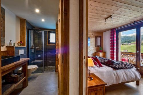 a bedroom with a bed and a bathroom with a tub at Chalet Sandy in Les Gets