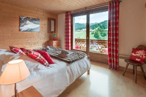 une chambre avec un lit et une grande fenêtre dans l'établissement Chalet Sandy, aux Gets