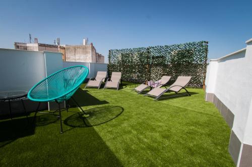 a patio with chairs and grass on a roof at Holidays2Malaga Suites in Málaga