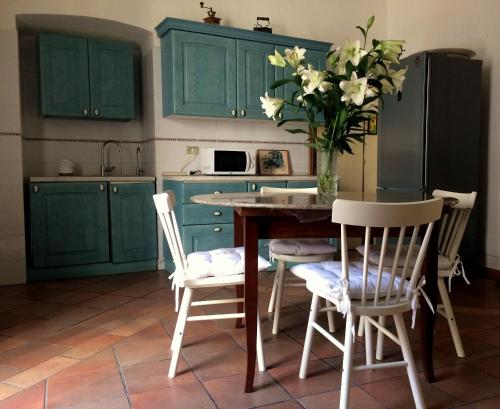 a kitchen with green cabinets and a table with a vase of flowers at Palazzo Framarino dei Malatesta - Noble Floor - XIV Century in Giovinazzo