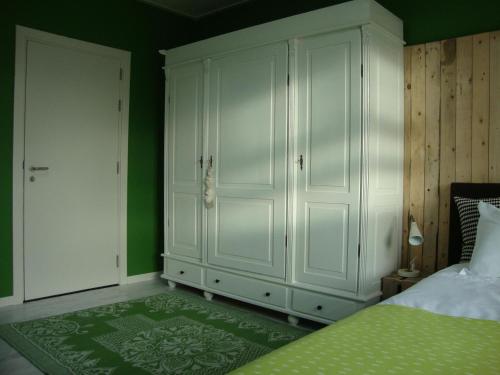 a bedroom with white cabinets and a green wall at Logement-B&B Safier in Joure