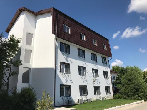 a white building with a brown roof at Pensiunea Otopeni in Otopeni