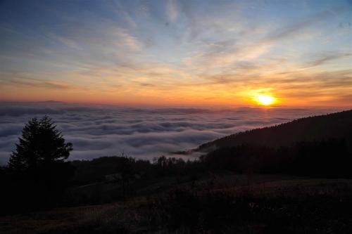 a view of the sun rising above a layer of clouds at Rooms Kozmus in Brestanica