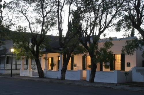 une maison blanche avec des arbres devant elle dans l'établissement De Kothuize 16, à Graaff-Reinet