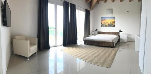 a bedroom with a bed and a chair and window at Agriturismo Villa Gaia in Lonato del Garda