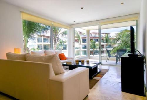 a living room with a white couch and a tv at The Elements Oceanfront & Beachside Condo Hotel in Playa del Carmen