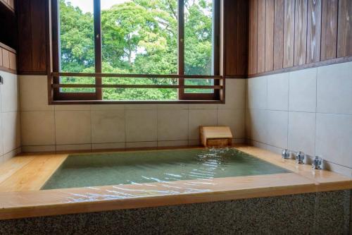 a jacuzzi tub in a room with a window at Ryokan Oomuraya in Ureshino