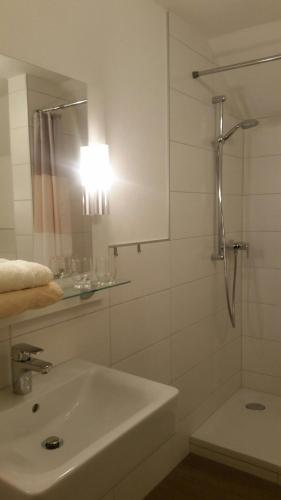 a bathroom with a sink and a shower with a mirror at Hotel-Pension Haus Hubertus in Weigendorf