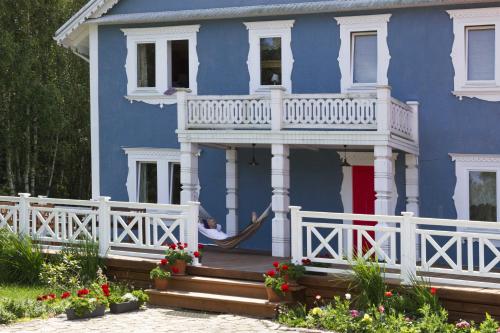 une maison bleue avec une véranda et une clôture blanche dans l'établissement Uroczysko Sosnówka, à Orzeszkowo
