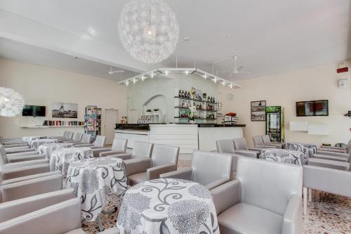 una stanza con sedie e tavoli bianchi e un lampadario a braccio di Hotel Garden a Bellaria-Igea Marina