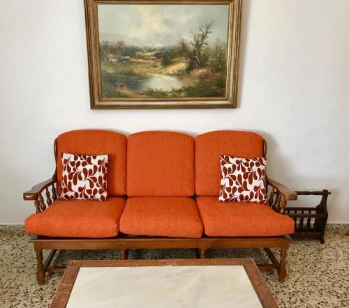 ベニドルムにあるApartamentos Nereの壁画のある部屋のオレンジ色のソファ