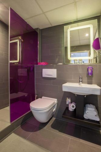 a purple bathroom with a toilet and a sink at Park Inn by Radisson Nürnberg in Nuremberg