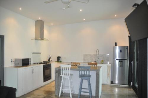 a kitchen with white cabinets and a counter with stools at Show Pony Beach Resort and Suites in Las Lajas