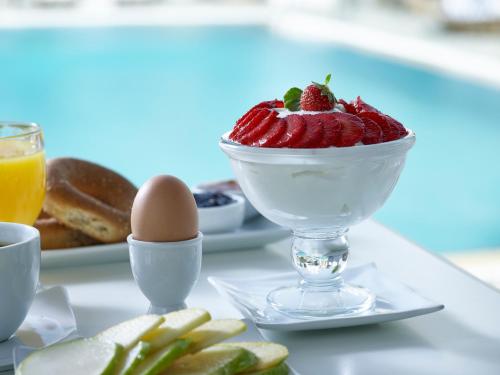 a table topped with a bowl of strawberries and eggs at Folegandros Apartments in Chora Folegandros