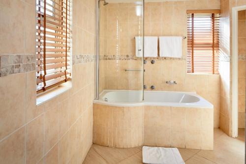a bathroom with a tub and a shower at First Group Port Owen Marina in Velddrif