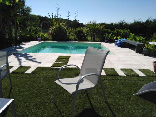 una silla blanca sentada junto a una piscina en Maison à la campagne en Lavergne