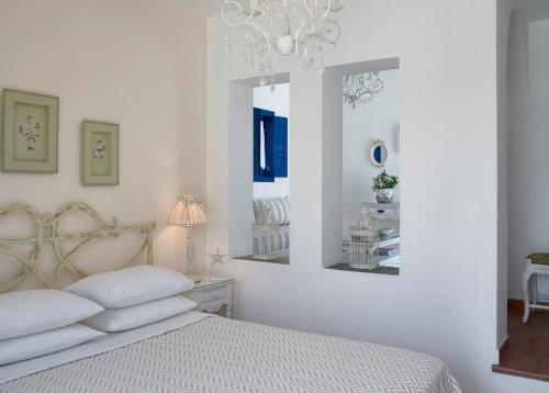 a white bedroom with a bed and a chandelier at Folegandros Apartments in Chora Folegandros