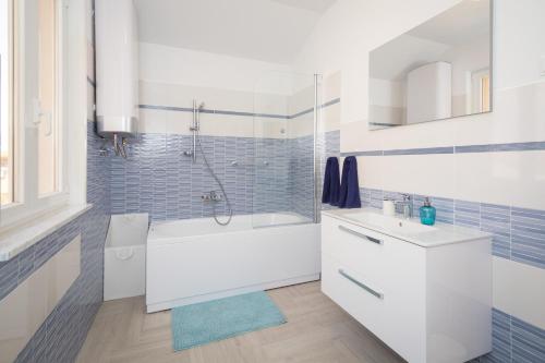 a white bathroom with a tub and a sink at Apartments Tamburini in Rovinj