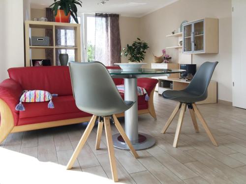 a living room with a red couch and a table and chairs at Ferienwohnung *Richi* in Sassnitz