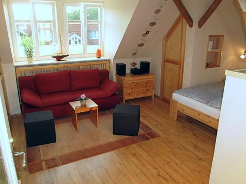 グラール・ミューリッツにある“Haus am Küstenwald” Ferienwohnungenのリビングルーム(赤いソファ、ベッド付)