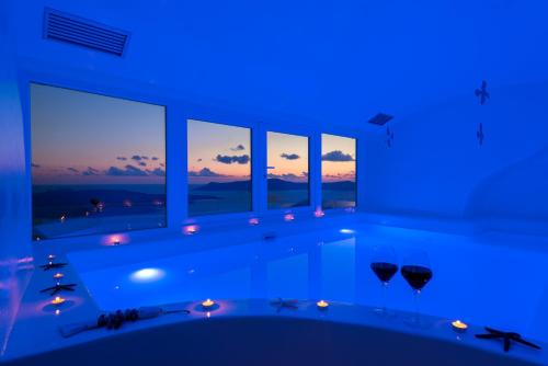 Habitación azul con bañera y ventana en Fira Deep Blue Suites en Fira