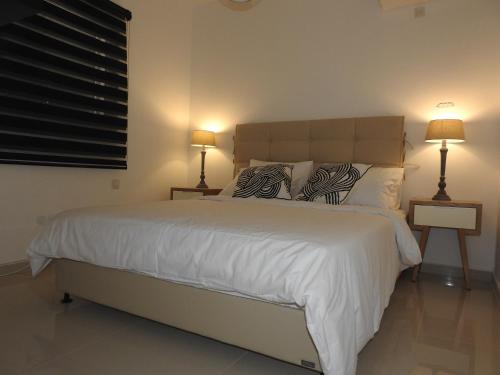 a bedroom with a large white bed with two lamps at ERA home boutique in Eilat