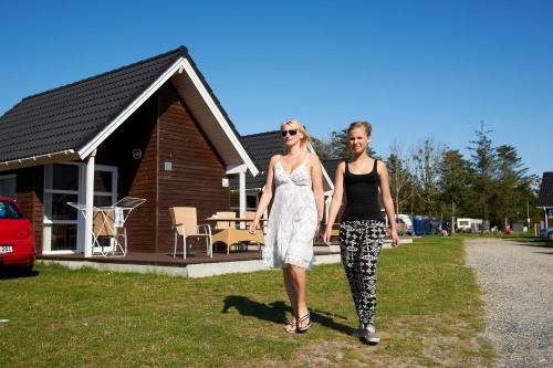 two women are standing in front of a house at Løkken Klit Camping & Cottage Village in Løkken