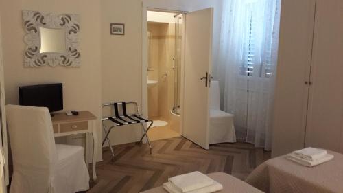 een witte kamer met een bureau, een televisie en een badkamer bij B&B IL TABERNACOLO in Florence