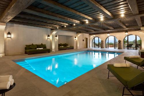 a large swimming pool with blue water in a building at Airelles Gordes, La Bastide in Gordes