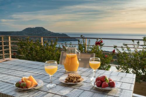 a table with two glasses of orange juice and fruit at Stella in the Village Suites in Plakias