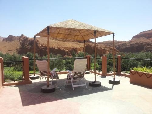 a patio with two chairs and an umbrella at Auberge Des Jardins du Dades in Boumalne Dades
