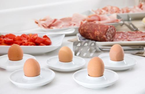 a table topped with egg cups and plates of food at Hotel Club Due Torri in Maiori