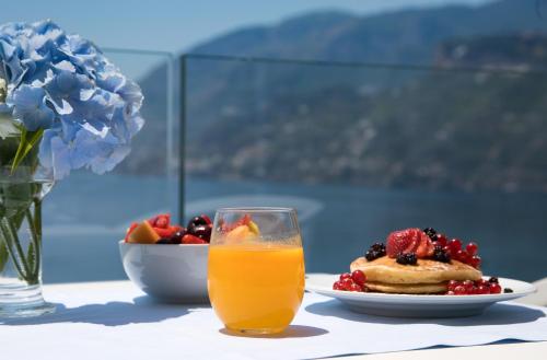 a table with a glass of orange juice and a plate of fruit at Hotel Club Due Torri in Maiori