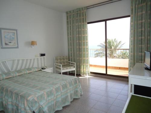 - une chambre avec un lit et un balcon avec une télévision dans l'établissement Hotel las Conchas, à La Rábita