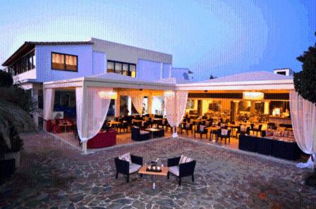 a building with a restaurant with tables and chairs at Venus Beach Hotel in Nea Stira