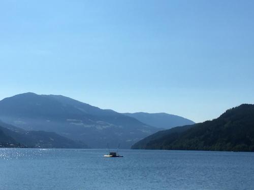 a boat in the middle of a lake with mountains at Pension & Apartments Ertl in Seeboden