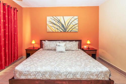 1 dormitorio con 1 cama con paredes de color naranja y 2 lámparas en Penthouse Jazmin - Downtown Playa del Carmen - At Margaritas II Condos, en Playa del Carmen